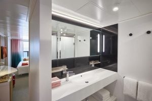 Virgin Voyages XL Sea Terrace marble bathroom with dual vanity, backlit mirror, and rainfall shower.
