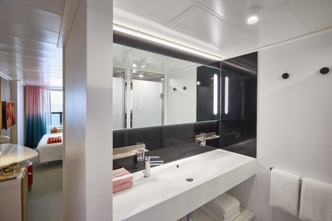 Virgin Voyages XL Sea Terrace marble bathroom with dual vanity, backlit mirror, and rainfall shower.