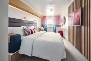 Virgin Voyages Sea View cabin bright bedroom with queen bed and ocean-view porthole