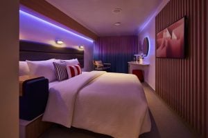 Virgin Voyages Sea View cabin queen bed with mood lighting and porthole window