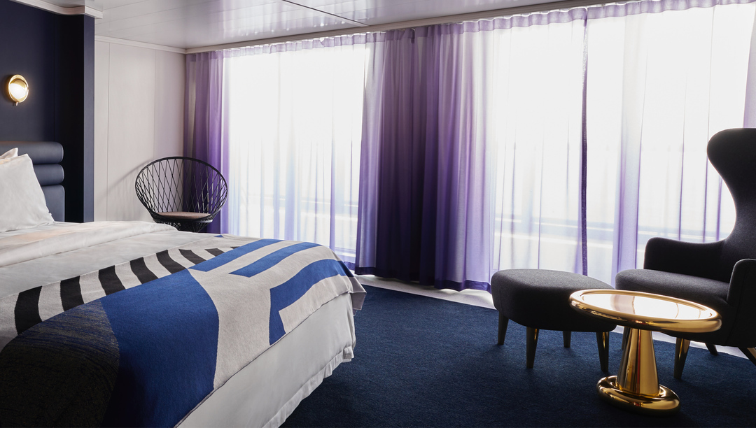 Virgin Voyages Posh Suite bedroom with king bed and purple drapes